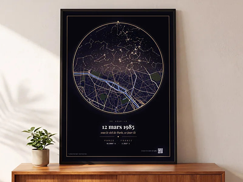 Affiche Ce Jour-Là encadrée en grand format, posée sur un buffet en bois dans une lumière douce : le ciel étoilé et le plan de la ville réunis sur fond nuit